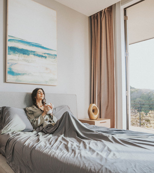 serene woman in bed smelling the morning coffee 